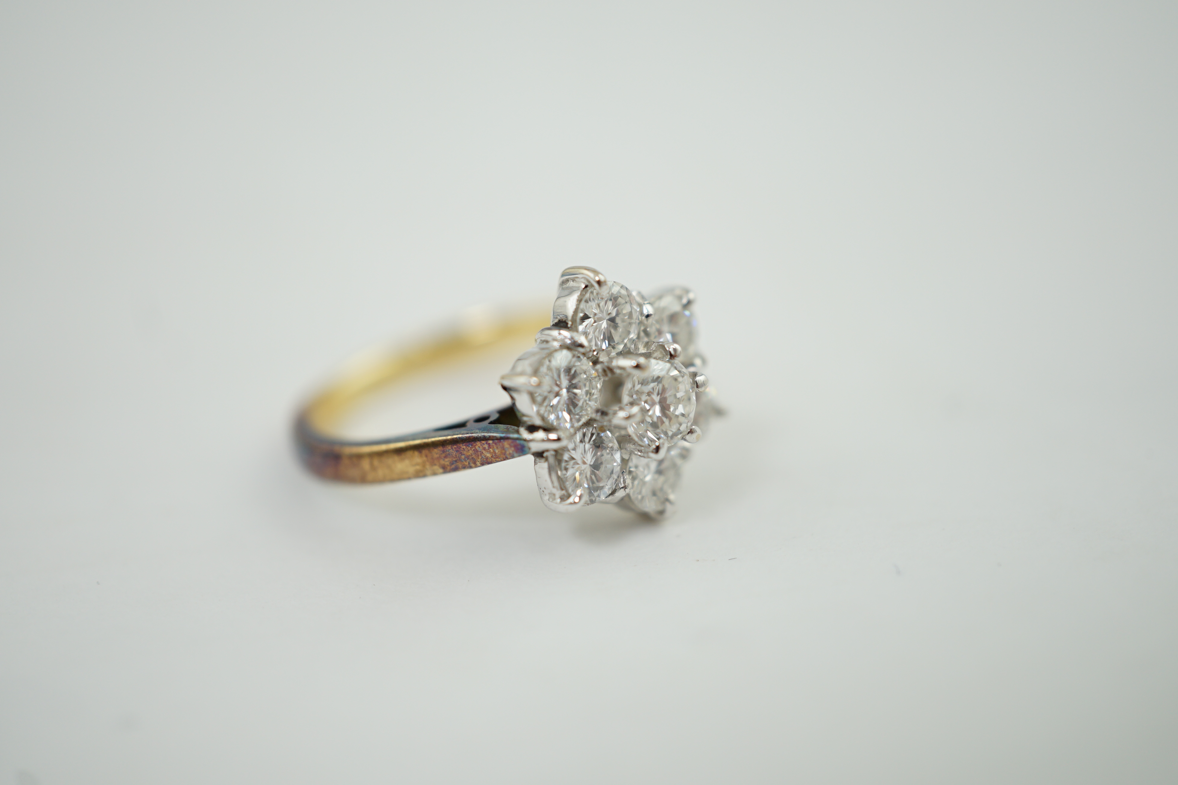 A modern 18ct gold and seven stone diamond set flower head cluster ring